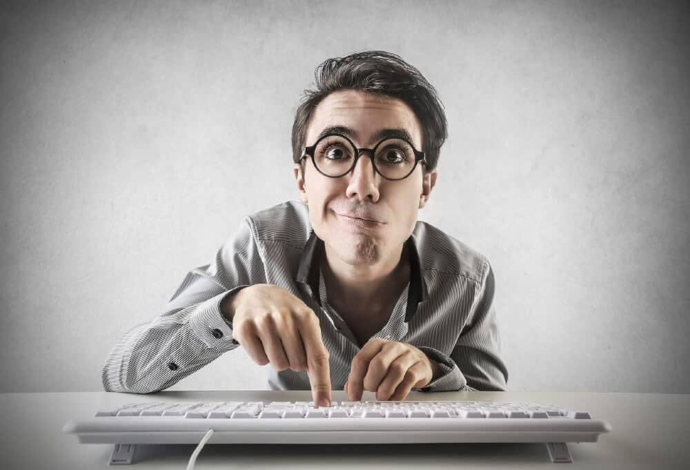 Man in gray shirt typing on a white keyboard at desk, digital marketing focus by Make It Loud Digital Marketing