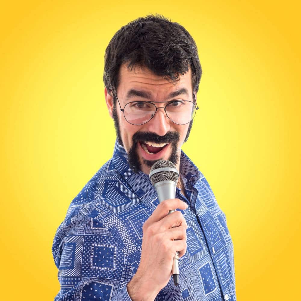 Man in blue patterned shirt holds microphone, yellow background, marketing presentation concept for Make It Loud Digital Marketing.